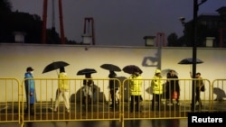 Police officers keep watch near barricades set up along Julu Road where people in Halloween costumes gathered the year before, in Shanghai, China, October 26, 2024. 