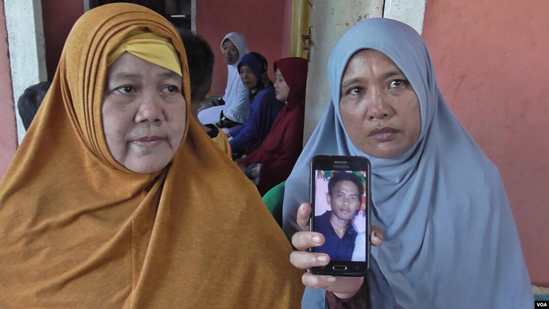 Roslian, 44 tahun (kanan) memperlihatkan foto putranya, Rinaldi, salah satu dari 10 WNI yang disandera oleh kelompok gerilyawan Abu Sayyaf di Filipina selatan (VOA/Yoanes).