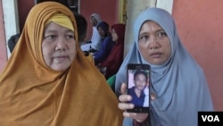Roslian, 44 (kanan), memperlihatkan foto putranya, Rinaldi, salah satu dari 10 WNI yang disandera oleh kelompok gerilyawan Abu Sayyaf di Filipina selatan. (VOA/Yoanes Litha).