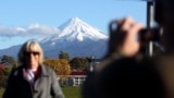 FILE - A man takes a picture of his wife with Mount Taranaki, also known as Mount Egmont, in the background in New Plymouth, New Zealand, Sept. 26, 2011. (AP Photo/Dita Alangkara, File)