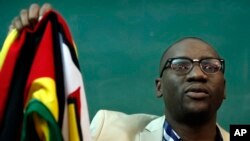 FILE - Zimbabwean Pastor Evan Mawarire holds his country's flag before addressing supporters at the University of the Witwatersrand in Johannesburg, South Africa, July 28, 2016.