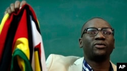 FILE - Zimbabwean Pastor Evan Mawarire holds his country's flag before addressing supporters at the University of the Witwatersrand in Johannesburg, South Africa, July 28, 2016.