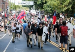 FILE - White nationalist demonstrators walk through town after their rally was declared illegal near Lee Park in Charlottesville, Va., Aug. 12, 2017.