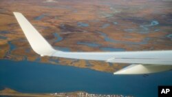 FILE - Air Force One, carrying President Barack Obama, flies over the island village of Kivalina, an Alaska Native community of 400 people already receding into the ocean as a result of rising sea levels, on its way to Ralph Wien Memorial Airport, Sept. 2, 2015, in Kotzebue, Alaska.