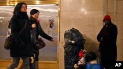 Commuters pass by a homeless person in Grand Central Terminal in New York, January 25, 2013. Sequestration could force deep cuts to social programs, including homeless services.