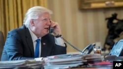 FILE - President Donald Trump speaks on the phone in the Oval Office at the White House in Washington, Jan. 28, 2017. 