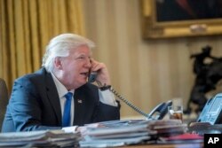 FILE - President Donald Trump speaks on the phone with Russian President Vladimir Putin, Jan. 28, 2017, in the Oval Office at the White House in Washington.