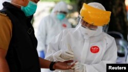 Seorang petugas medis mengenakan baju pelindung mengambil sampel darah dari seorang pria untuk tes virus corona (Covid-19) di Bogor, Jawa Barat, 7 April 2020. (Foto: Reuters)