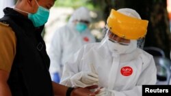 Seorang petugas medis mengenakan baju pelindung mengambil sampel darah dari seorang pria untuk tes virus corona (Covid-19) di Bogor, Jawa Barat, 7 April 2020. (Foto: Reuters)