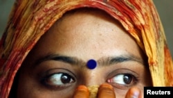 FILE - A woman wearing a bindi waits after casting her vote at a polling station in the old quarters of Delhi.