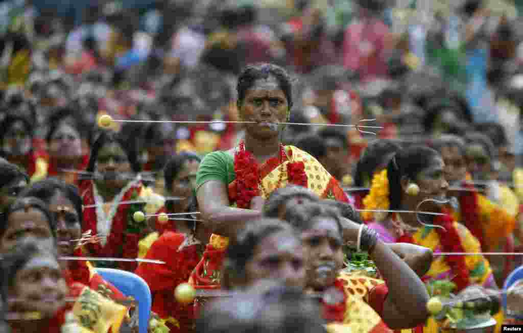 Devotees with their mouths pierced with tridents participate in a ritual to worship the Hindu goddess Durga during Aadi festival celebrations in the southern Indian city of Chennai.