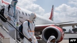 Pasajeros usando trajes de protección desembarcan de un avión en el aeropuerto internacional de Nairobi, Kenia, el 19 de enero.