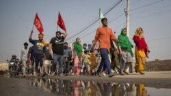 A group of protesters shout slogans as they arrive to join farmers demanding to abolish new farming laws they say will result in exploitation by corporations, eventually rendering them landless, at the Delhi-Haryana state border, India, Dec. 1, 2020.