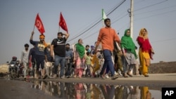 A group of protesters shout slogans as they arrive to join farmers demanding to abolish new farming laws they say will result in exploitation by corporations, eventually rendering them landless, at the Delhi-Haryana state border, India, Dec. 1, 2020.