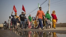 A group of protesters shout slogans as they arrive to join farmers demanding to abolish new farming laws they say will result in exploitation by corporations, eventually rendering them landless, at the Delhi-Haryana state border, India, Dec. 1, 2020.