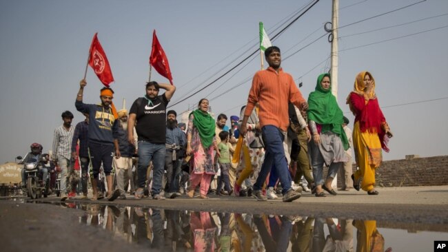 A group of protesters shout slogans as they arrive to join farmers demanding to abolish new farming laws they say will result in exploitation by corporations, eventually rendering them landless, at the Delhi-Haryana state border, India, Dec. 1, 2020.