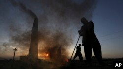 FILE - Day laborers work at a brick factory near Kabul, Afghanistan, April 20, 2015. The men work eight hours a day, six days a week, and make about 350 Afghani ($6) daily. A new U.N. report urges equitable work for all.