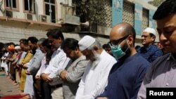 A man wears a protective mask as a preventive measure amid coronavirus fears, as he attends Friday prayers with others in Karachi, Pakistan, March 13, 2020. 