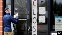 In this April 30, 2020 file photo, a man writes information in front of Illinois Department of Employment Security in Chicago.
