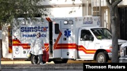 A paramedic dressed in personal protective equipment exits an ambulance at St. Petersburg General Hospital in Florida