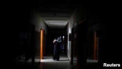 A Palestinian woman carries her sick child as she walks through the corridor at Durra hospital in Gaza City, Feb. 6, 2018. 