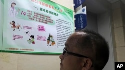 A visitor to a hospital looks at a poster with information on rabies vaccine in Beijing, China, Monday, July 23, 2018. (AP Photo/Ng Han Guan)