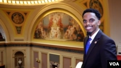 First-term legislator Omar Fateh shows off the Minnesota Senate chamber in the state Capitol in St. Paul. Behind him is the mural "Minnesota: Granary of the World." (Betty Ayoub/VOA) 