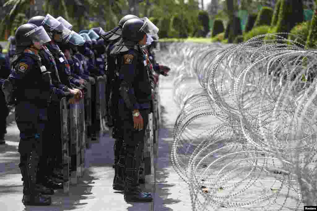 Riot police stand guard near barb wire inside the compound of the Thai Royal Police Club in Bangkok, Jan. 29, 2014. 