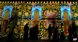 FILE- Visitors walk past a light show on the ancient mosque of Imam Shafi'i at the historical Jiddah old city, Saudi Arabia, April 6, 2017.