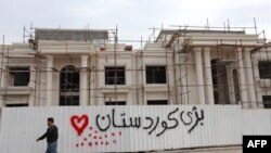 A man walks past graffiti reading in Kurdish "Long live Kurdistan,” near the scene of a rocket attack in Irbil, the capital of the northern Iraqi Kurdish autonomous region, Feb. 16, 2021. 