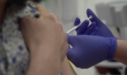 FILE - Screen grab taken from video issued by Britain's Oxford University, showing a person being injected as part of the first human trials in the UK to test a potential coronavirus vaccine, untaken by Oxford University, Apr. 23, 2020.