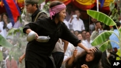 FILE: Cambodian students from the Royal University of Fine Arts re-enact torture executed by the Khmer Rouge during their reign of terror in the 1970s to mark the annual Day of Anger at Choeung Ek, a former Khmer Rouge "killing field" dotted with mass graves, on the outskirts of Phnom Penh, Cambodia, Tuesday, May 20, 2014. (AP Photo/Heng Sinith)