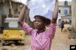 A woman carry bags of water she bought on a street in Baruwa Lagos, Nigeria, March 22, 2017.