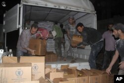 FILE - This photo provided by the Syrian anti-government activist group Local Council of Daraya City, which has been authenticated based on its contents and other AP reporting, shows Syrian citizens load food and other supplies from a truck that entered the besieged town of the rebel-held suburb of Daraya, southwest of Damascus, Syria, June 10, 2016.