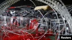 Riot police cover themselves with shields as they guard behind barb wires during a pro-democracy rally demanding Prime Minister Prayuth Chan-ocha to resign and reforms to the monarchy, at 11th Infantry Regiment, in Bangkok, Nov. 29, 2020.