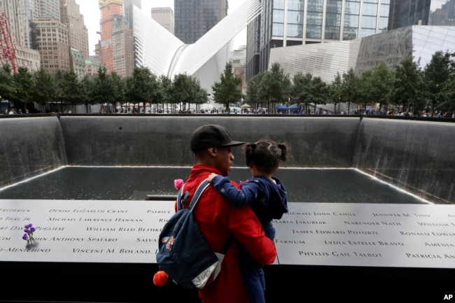Un hombre y su hija observan la fuente norte en el World Trade Center en Nueva York durante la ceremonia recordatorai de los ataques terroristas de 2001 el martes, 11 de septiembre de 2018.
