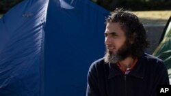 FILE - Abu Wa'el Dhiab, from Syria, sits in front of the U.S. embassy while visiting former fellow detainees demanding financial assistance from the U.S., in Montevideo, Uruguay, May 5, 2015.
