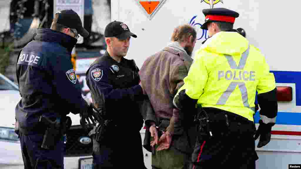 Police officers search a man arrested after approaching police tape near the National War Memorial while Prime Minister Stephen Harper paid respect to Cpl. Nathan Cirillo at the memorial in Ottawa, Oct. 23, 2014. 