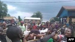 People argue as a woman is transported to the local hospital in Beni on August 15, 2016 during scenes of tension following a wave of unrest and violence in the region. At least 42 civilians have been killed in the eastern Democratic Republic of Congo, a local official said on August 14, in what the government described as a massacre in revenge for military operations in the area.