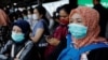 Para penumpang mengenakan masker saat menunggu kereta di sebuah stasiun di Jakarta, 2 Maret 2020. (Foto: Reuters)