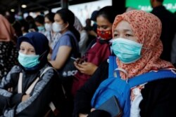 Para penumpang mengenakan masker saat menunggu kereta di sebuah stasiun di Jakarta, 2 Maret 2020.