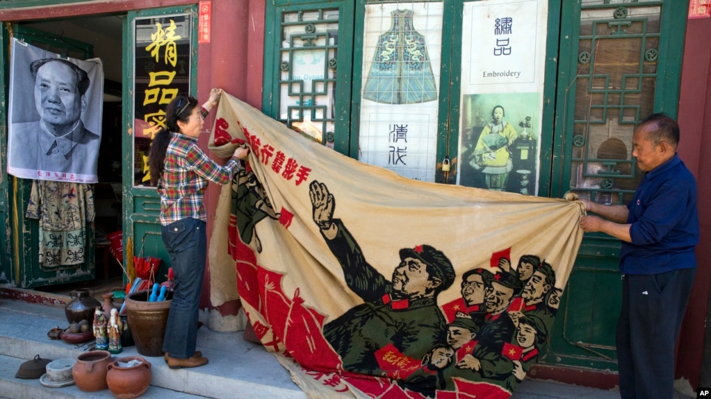 北京商販正在展示一麵畫有中國前領導人毛澤東在文革時期的宣傳旗。（2016年5月16日）