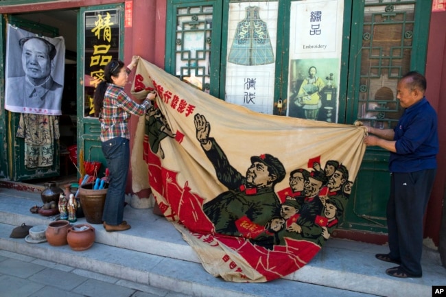 北京商贩正在展示一面画有中国前领导人毛泽东在文革时期的宣传旗。(2016年5月16日)
