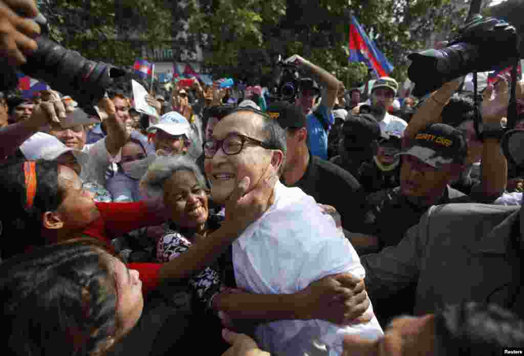 Sam Rainsy (C), president of the opposition Cambodia National Rescue Party (CNRP), is surrounded by his supporters as he arrives at a protest at the Freedom Park in central Phnom Penh. 