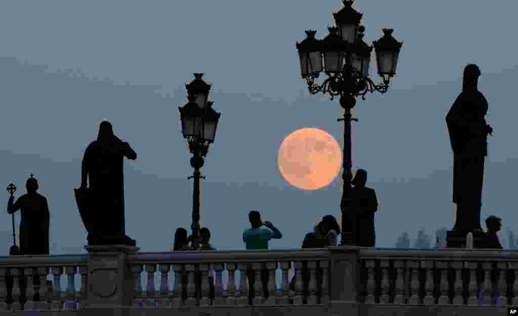 People take photos of a perigee moon also known as a supermoon as it rises above a bridge over Vardar River in Skopje, Macedonia, Sunday, Aug. 10, 2014.
