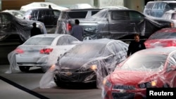 FILE - Newly-produced American vehicles are seen covered with protective wrap at an expo center in Detroit, Michigan.