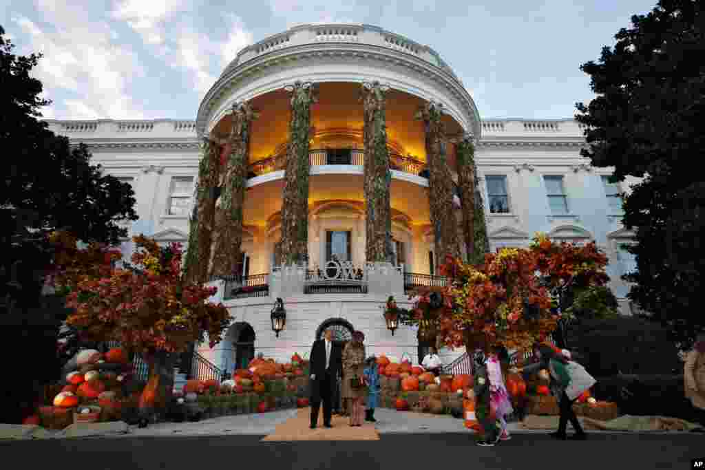 U.S. President Donald Trump and first lady Melania Trump give candy to children during a Halloween trick-or-treat event at the White House, Oct. 28, 2018, in Washington.