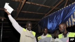 A poll worker holds up a ballot as vote counting begins in Kampala, February 18, 2011
