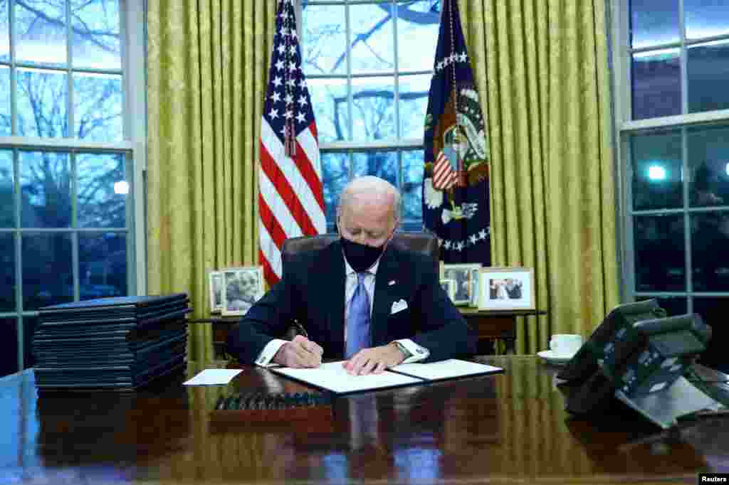 U.S. President Joe Biden signs executive orders in the Oval Office of the White House in Washington, after his inauguration as the 46th President of the United States, Jan. 20, 2021.