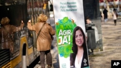 A woman walks past an election poster for the People, Animals, Nature Party at a bus stop in Lisbon, Jan. 20, 2022. 